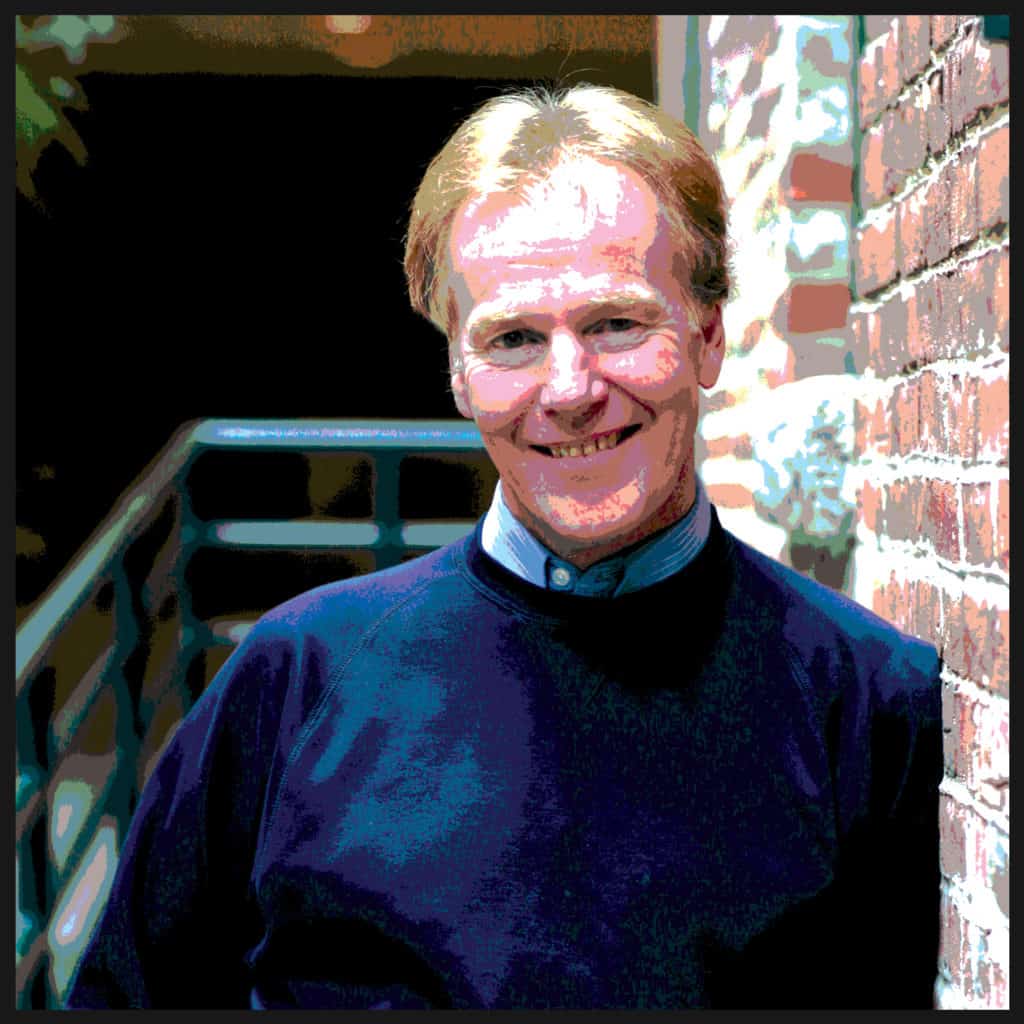 Photo of Otto Scharmer smiling and leaning against a brick wall.
